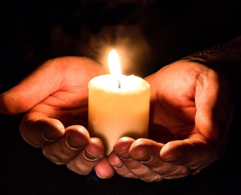 Open hands holding candles - Disaster Relief Fund